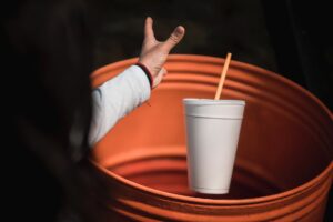 a person throwing a to go cup in a garbage can